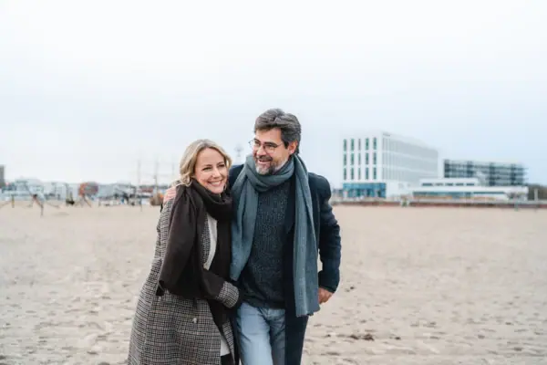 Ein Mann und eine Frau spazieren am Strand entlang.