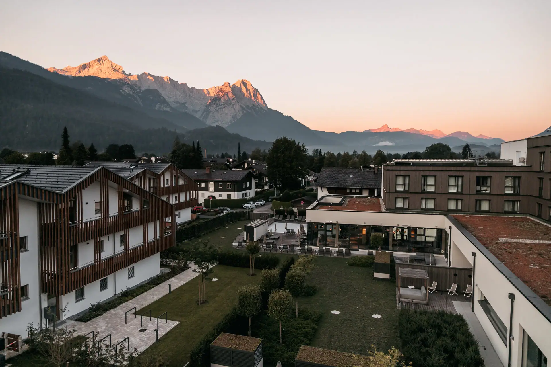 Eine Gruppe von Gebäuden mit Bäumen und Bergen im Hintergrund.