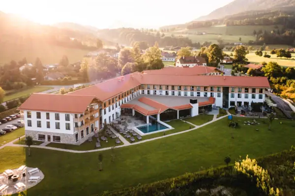 aja Hotel Ruhpolding Ein großes Gebäude mit einem Pool und Gras.