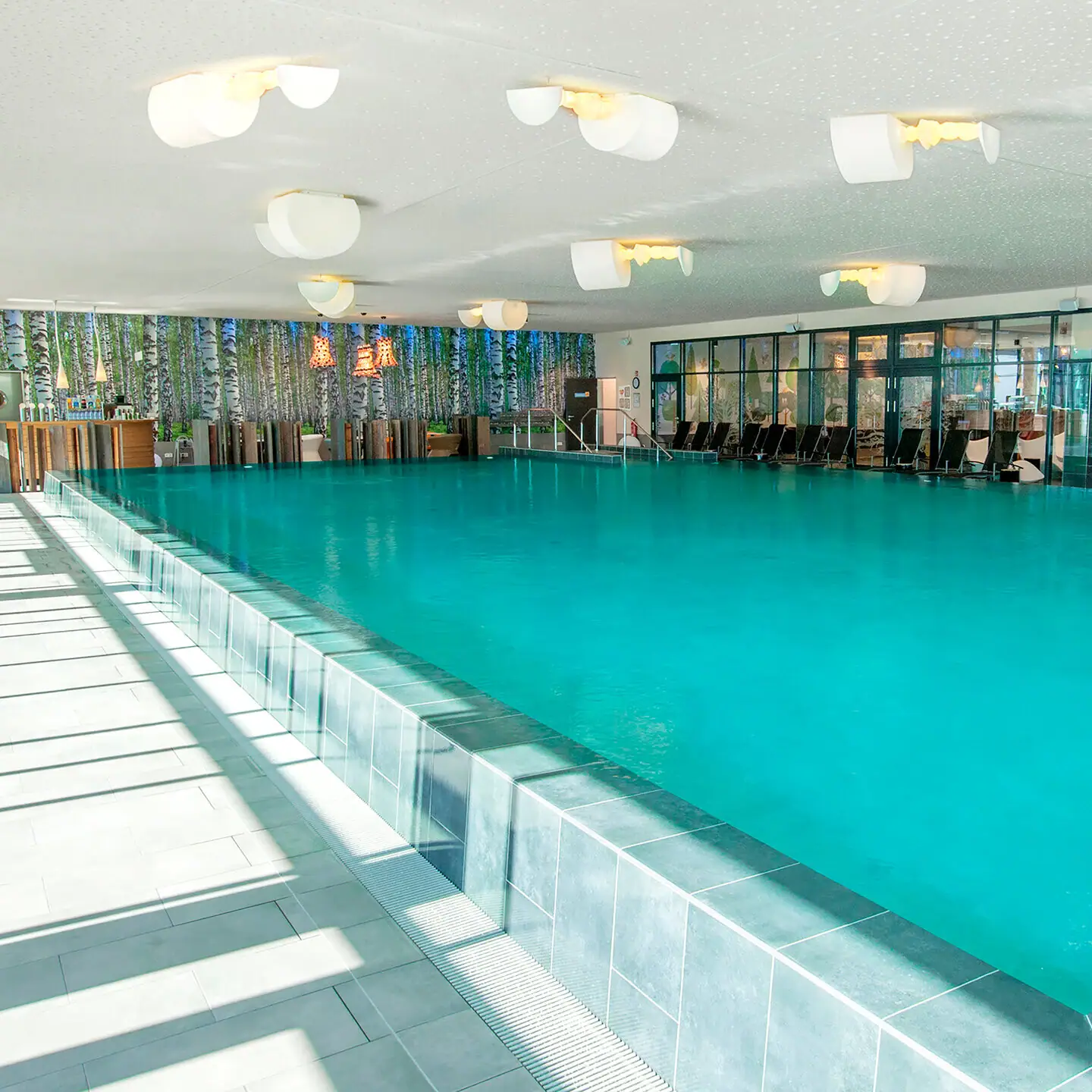 Ein Schwimmbecken mit Stühlen und Tischen.