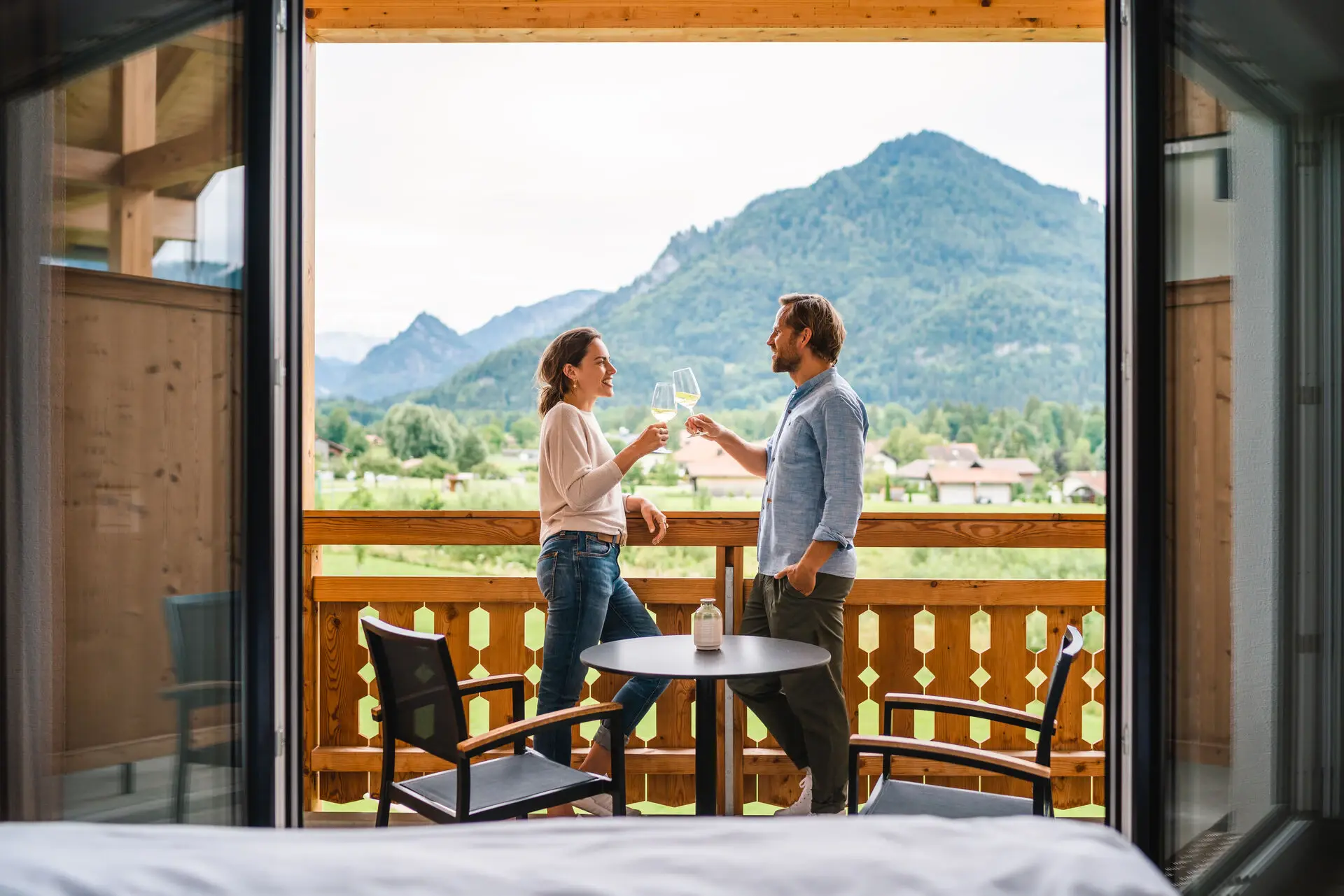 Mann und Frau halten Weingläser auf einem Balkon.