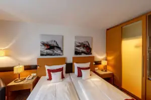 Doppelzimmer Ein Zimmer mit zwei Betten und Gemälden an der Wand.