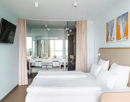 Zimmer im aja Travemünde Ein Zimmer mit einem Bett und einem Spiegel.