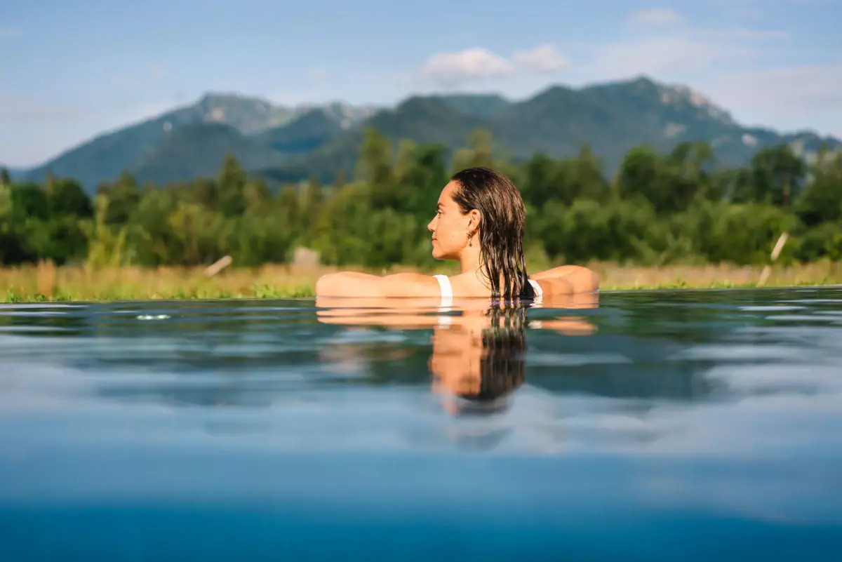 Outdoor Pool Ruhpolding Eine Frau in einem Outdoor Pool mit Blick auf die Berge.