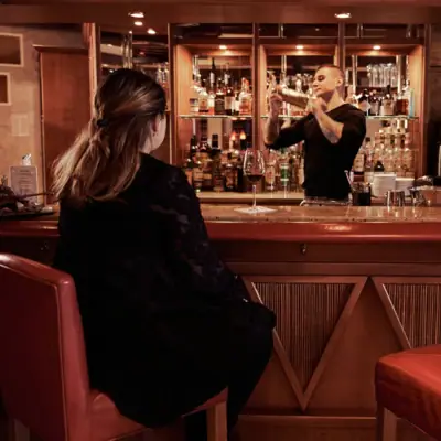 Ein Mann und eine Frau in schwarzen Kleidern sitzen an einer Bar.