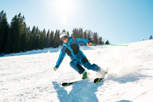 Eine Person fährt auf Skiern einen verschneiten Hang hinunter.