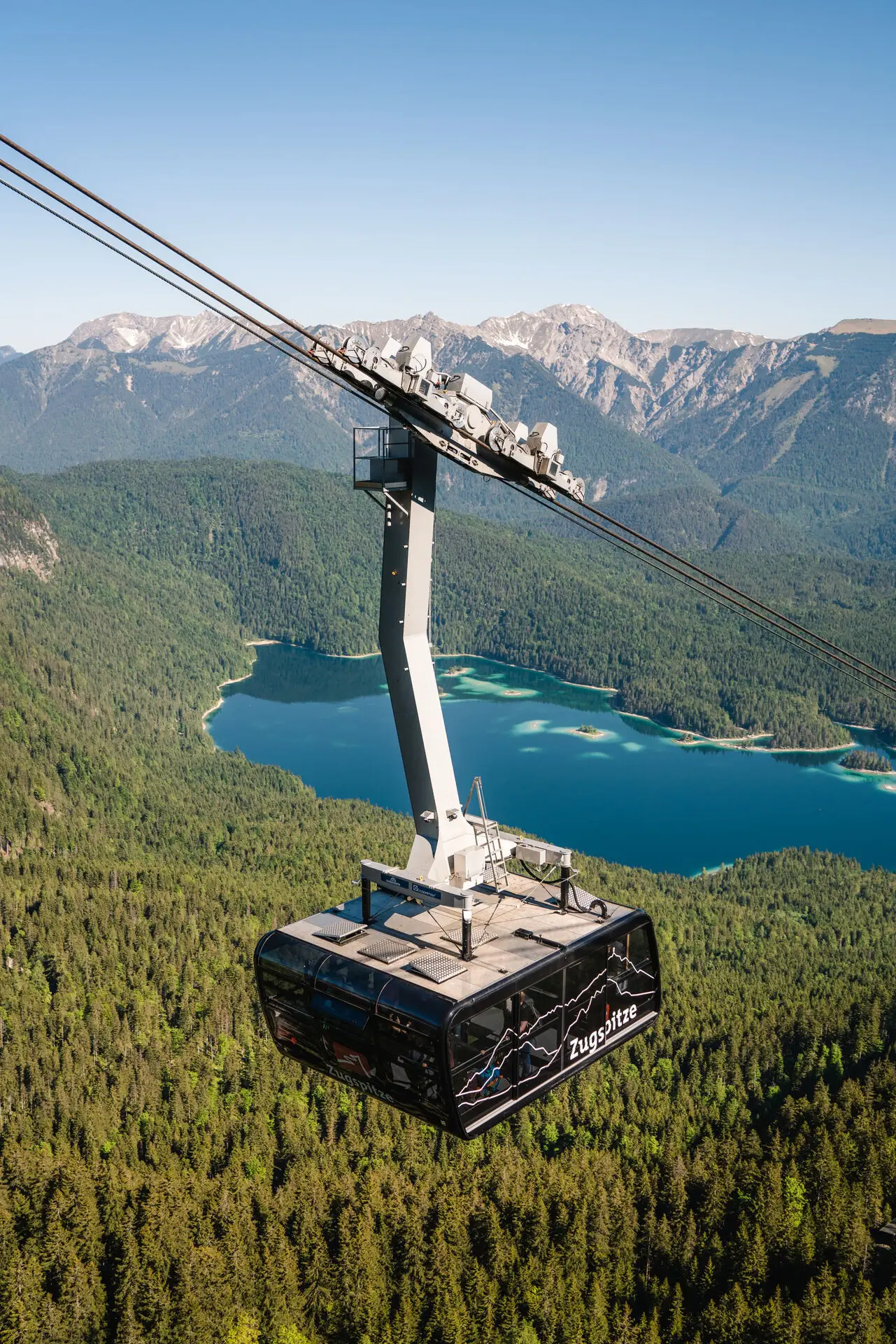 Seilbahn Zugspitze über dem Eibsee mit Bergkulisse im Hintergrund.