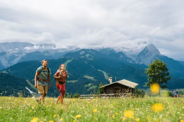 Ein Mann und eine Frau gehen in einem Feld mit Bergen im Hintergrund.