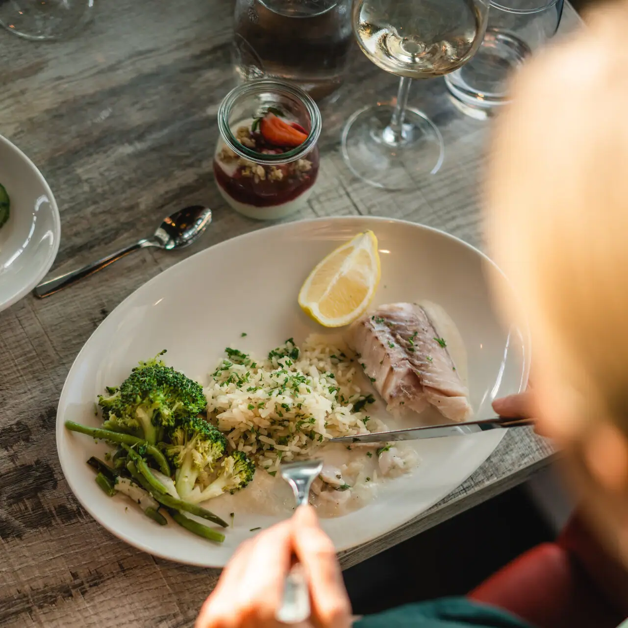 Fischgericht Eine Person isst von einem Teller mit Essen.