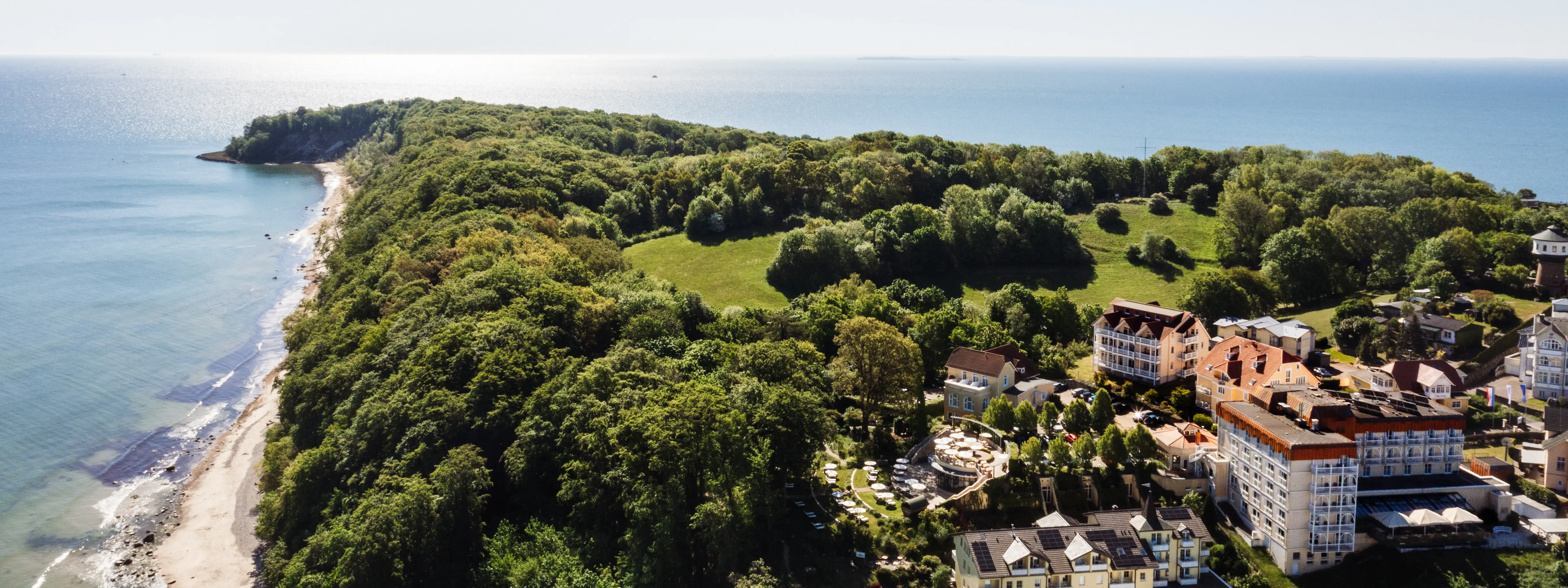 Landschaft mit Bäumen und Gebäuden am Küstenstreifen.