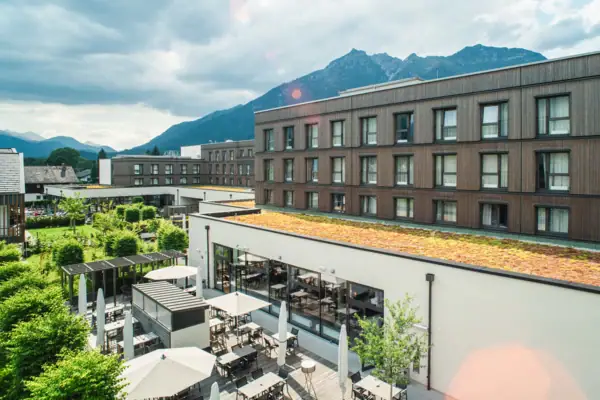 Ein Gebäude mit Dach, Tischen und Stühlen im Freien unter bewölktem Himmel.