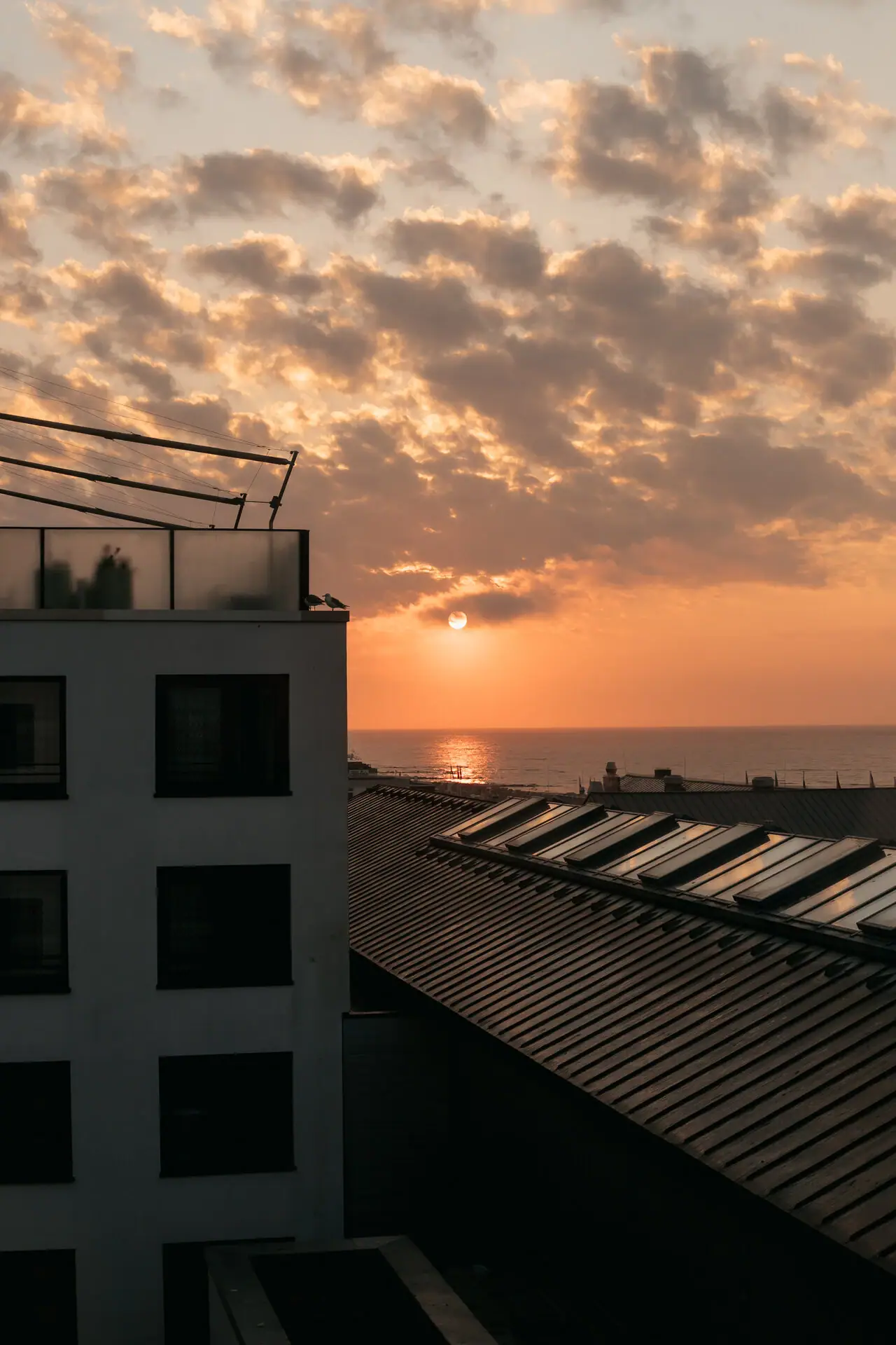 Ein Gebäude mit Dach vor einem Sonnenuntergang.
