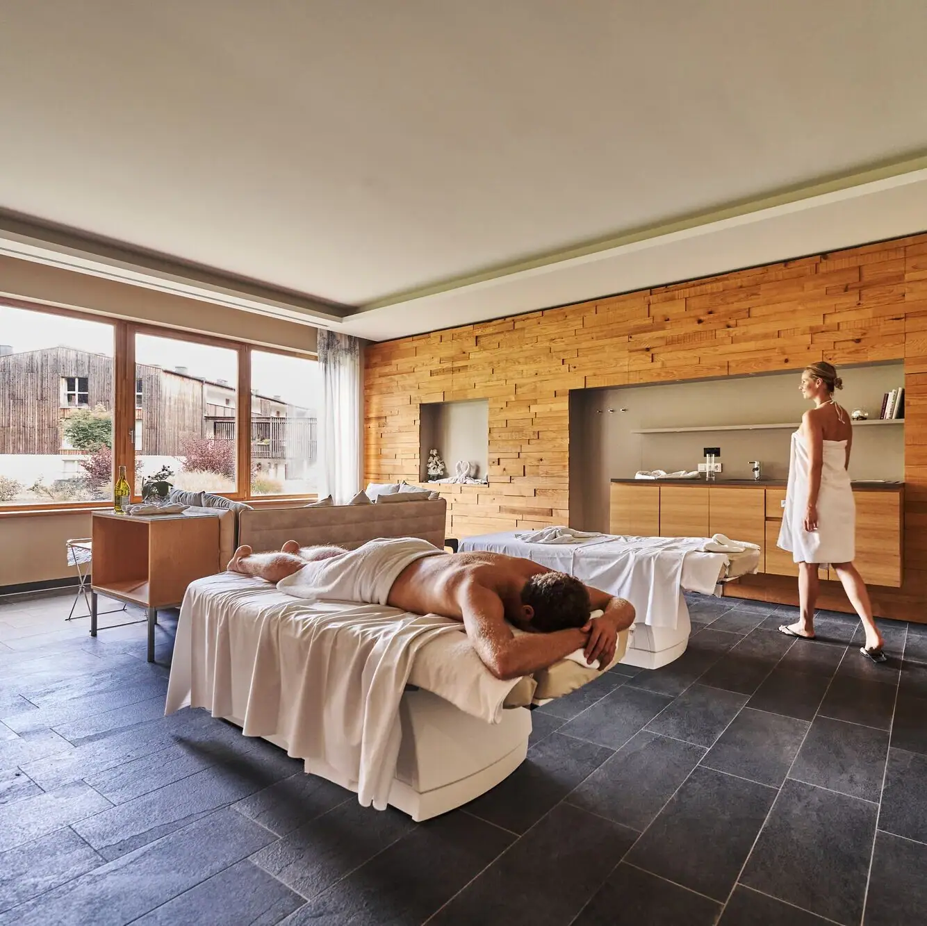 SPA Suite Ein Mann liegt auf einer Liege, während eine Frau hinter ihm steht.