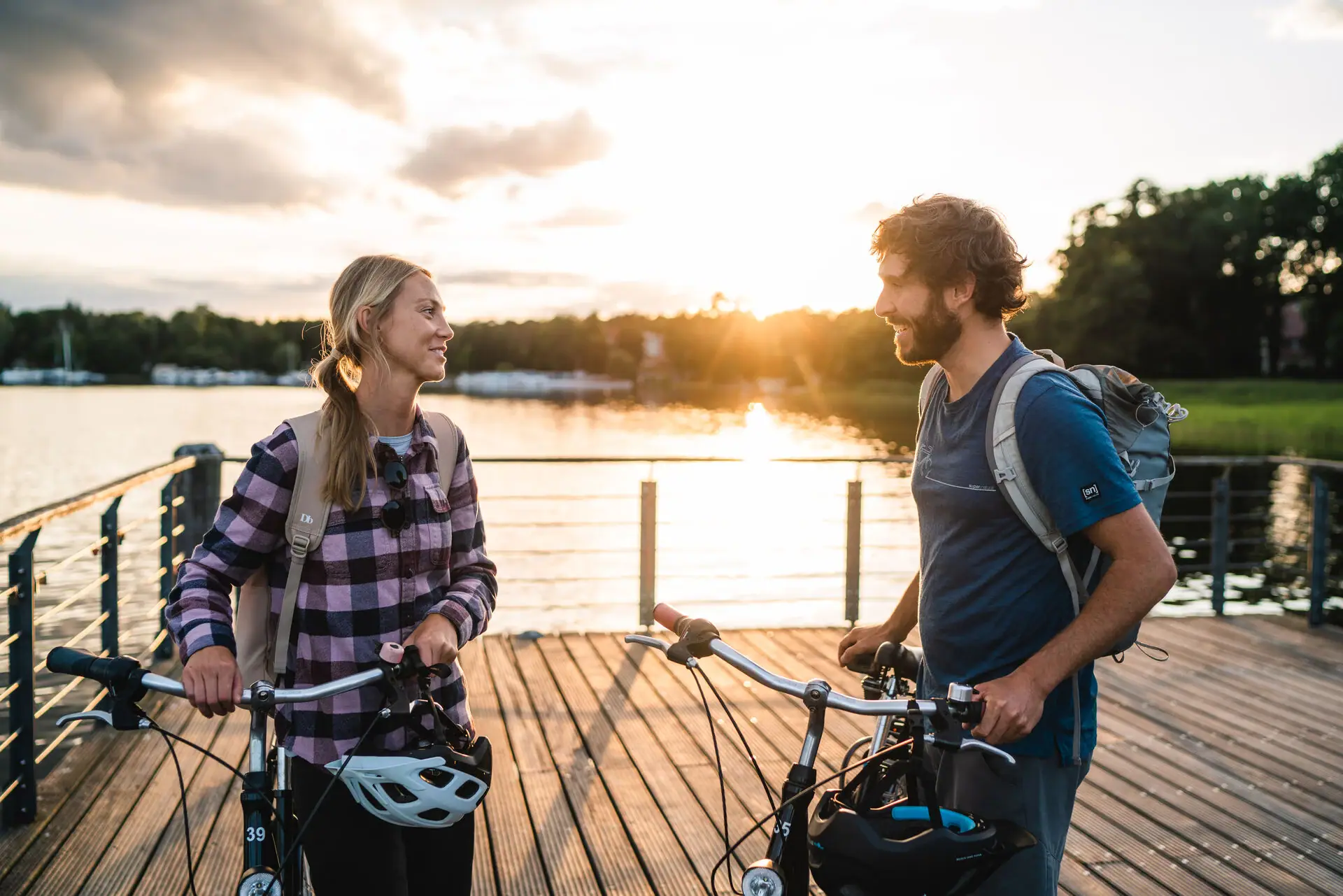Fahrradtour am Scharmützelsee Ein Mann und eine Frau stehen mit Fahrrädern auf einem Steg vor einem See.