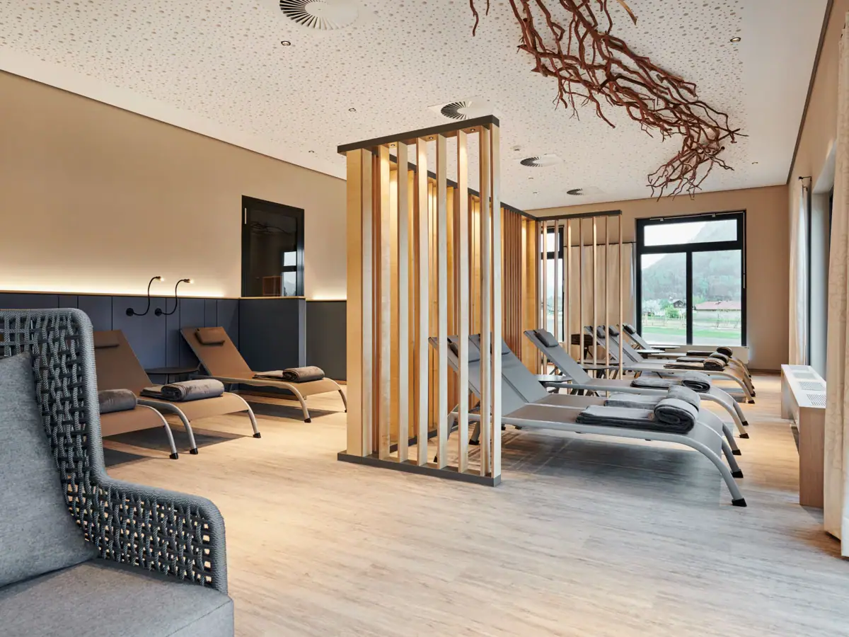 Ruhebereich in der Saunalandschaft im aja Ruhpolding Ein Raum mit Lounge-Stühlen und einer Holzstruktur.