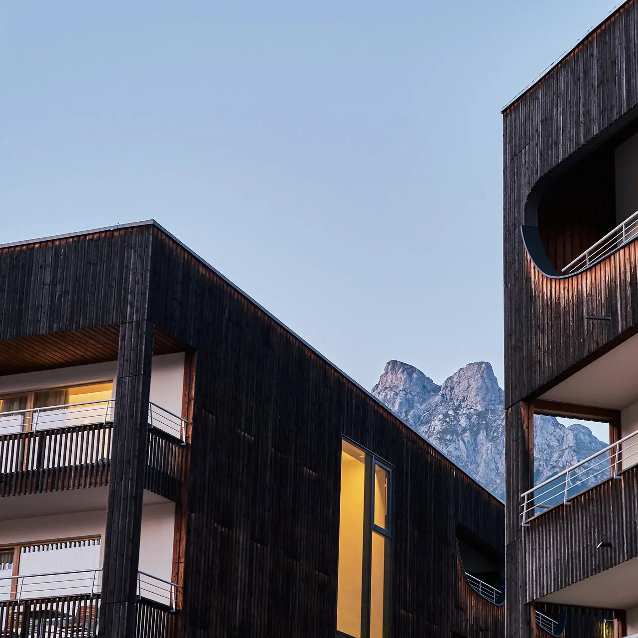 Eine Nahaufnahme des Hotelgebäudes mit Balkonen und den Bergen im Hintergrund.