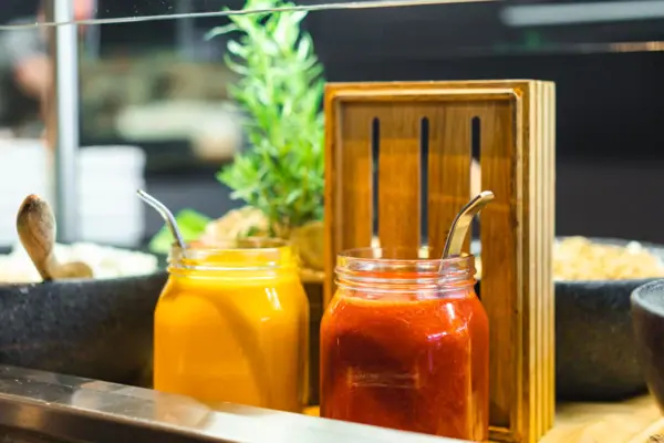 Buffet im JEDERMANNS Gläser mit Sauce und ein Löffel in einem Holzhalter