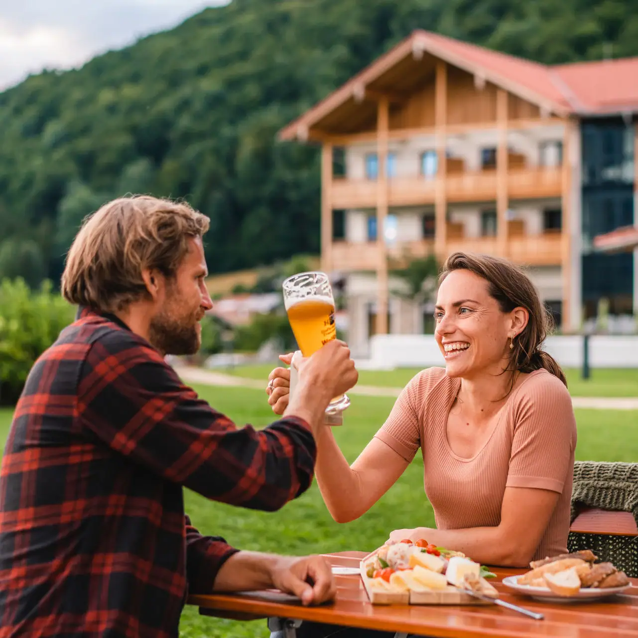 Biergarten aja Ruhpolding Ein Mann und eine Frau sitzen an einem Tisch mit Essen und Getränken.