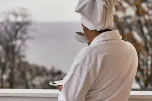 SPA Eine Person im weißen Bademantel mit einem Handtuch auf dem Kopf und einer Tasse Tee.