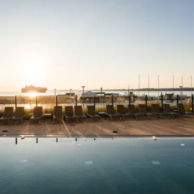 Ein Pool mit Stühlen und einem Boot im Hintergrund.