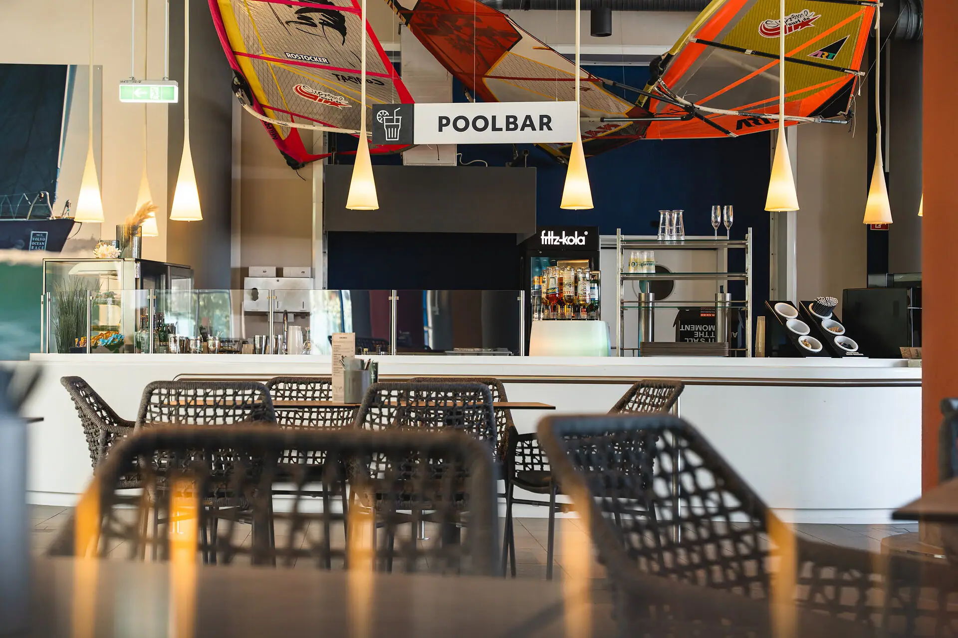 Poolbar im aja Warnemünde Eine Bar mit Tischen und Stühlen im Wellnessbereich