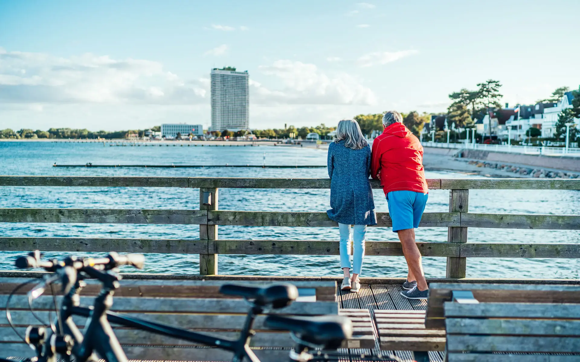 Ein Mann und eine Frau stehen auf der Seebrücke in Travemünde und blicken auf die Ostsee.