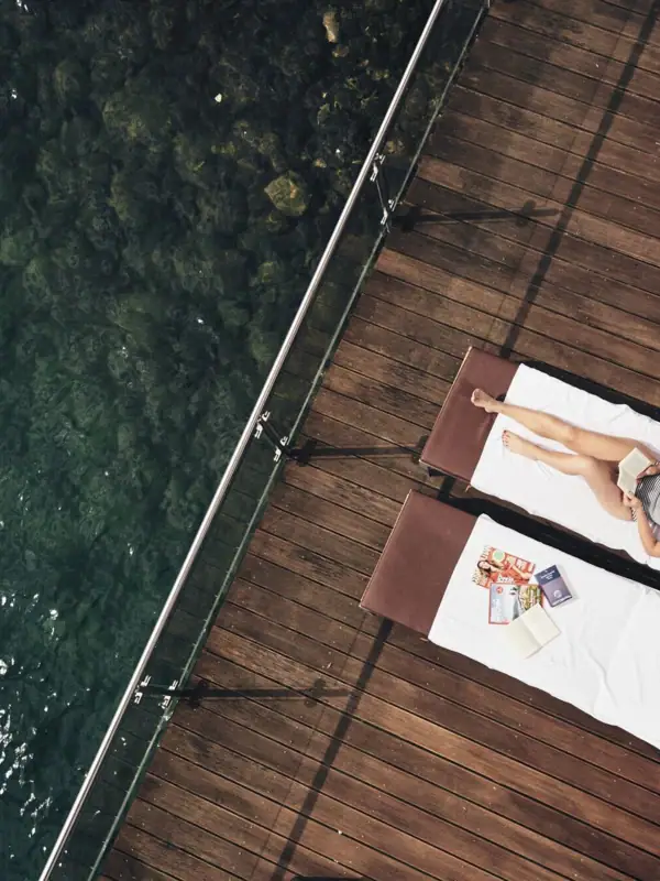 Eine Frau liegt auf einem Liegestuhl neben Wasser.