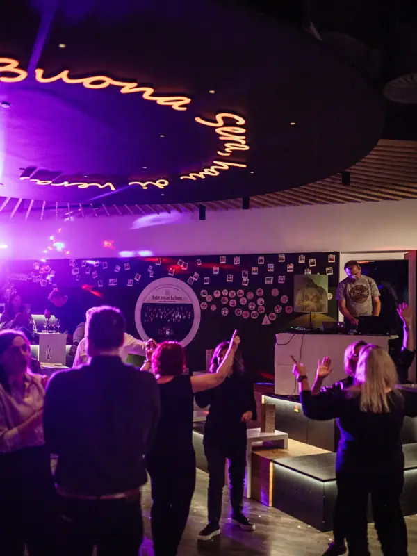 Eine Gruppe von Menschen in einem Raum mit einer Bühne und einem Schild.