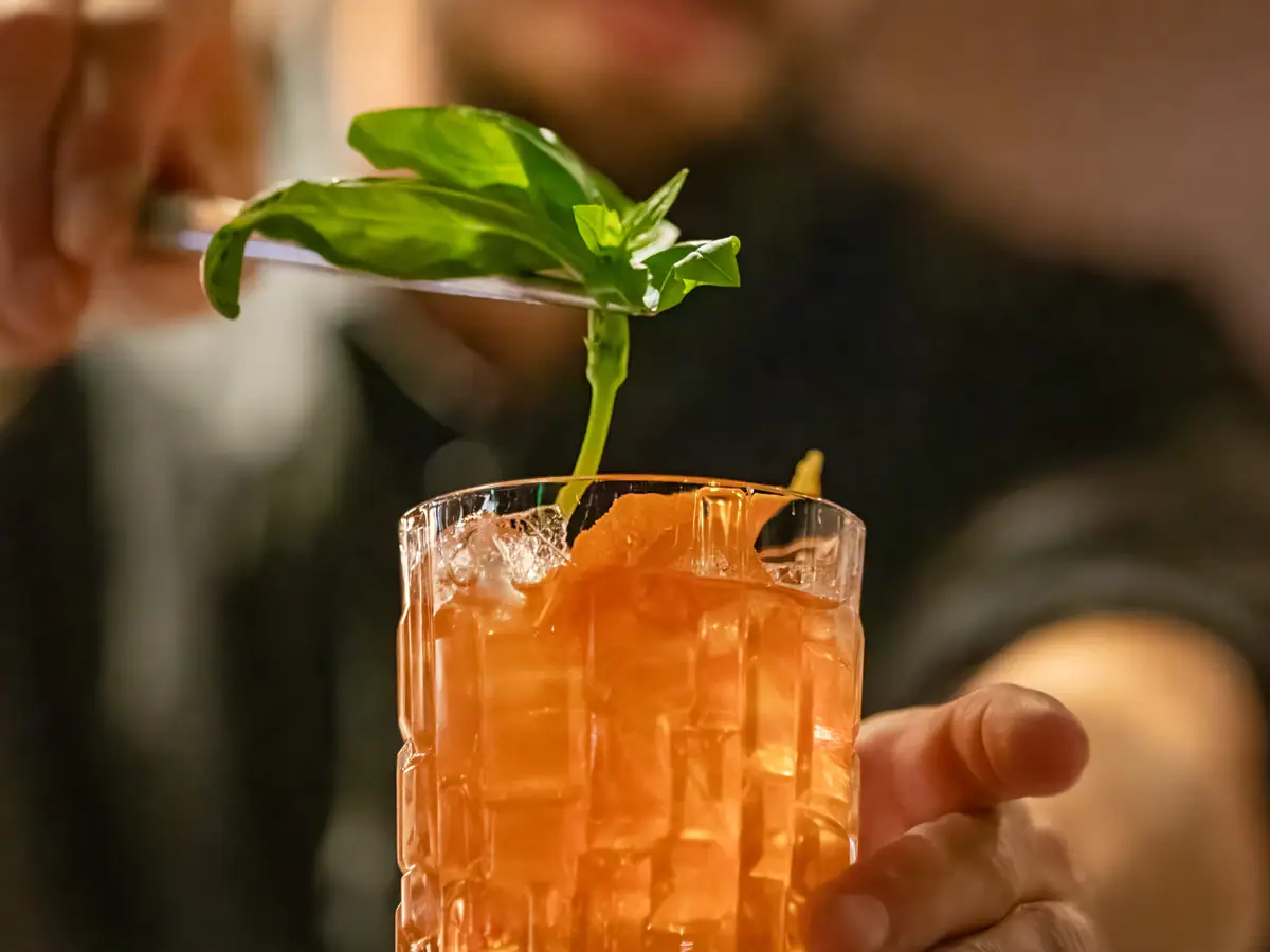 Ein Mann hält ein Messer über ein Glas mit einem Drink.