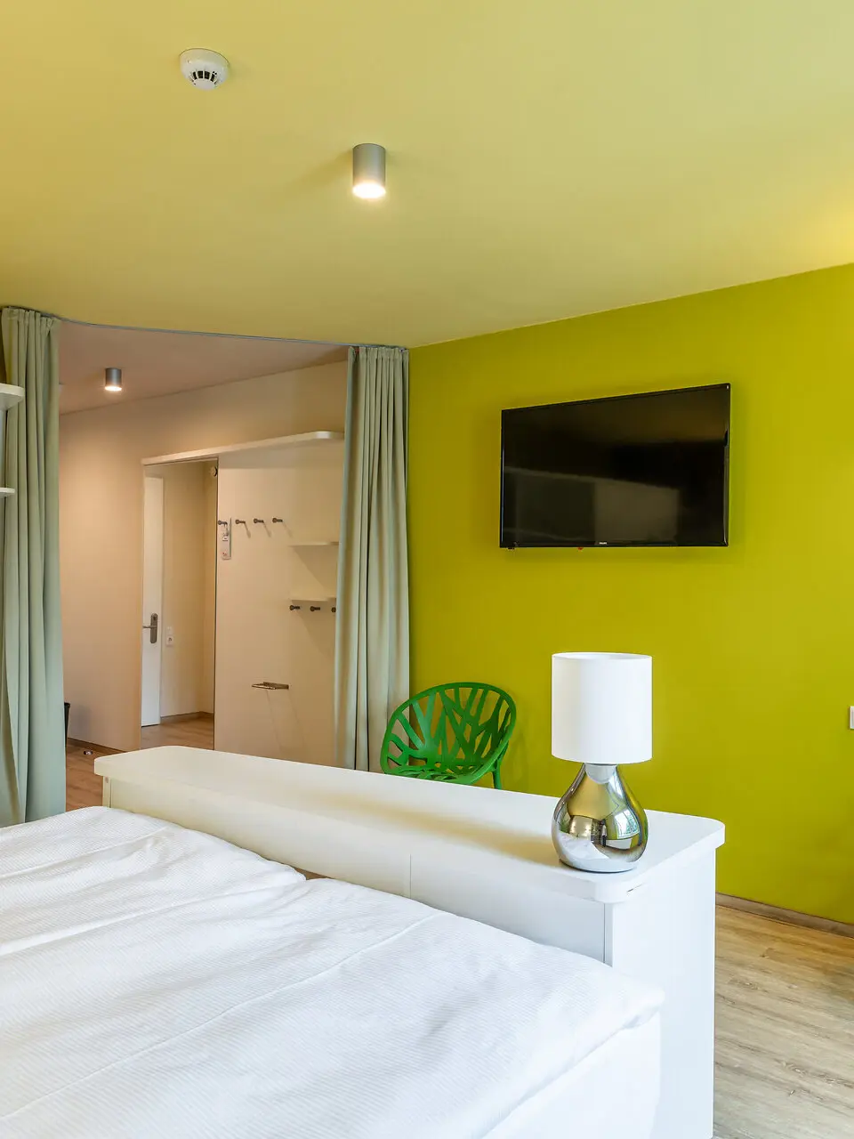 Ein Schlafzimmer mit grünen Wänden, einem Bett und moderner Einrichtung.