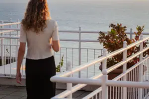 Eine Frau steht auf einem Deck mit Blick auf den Ozean.