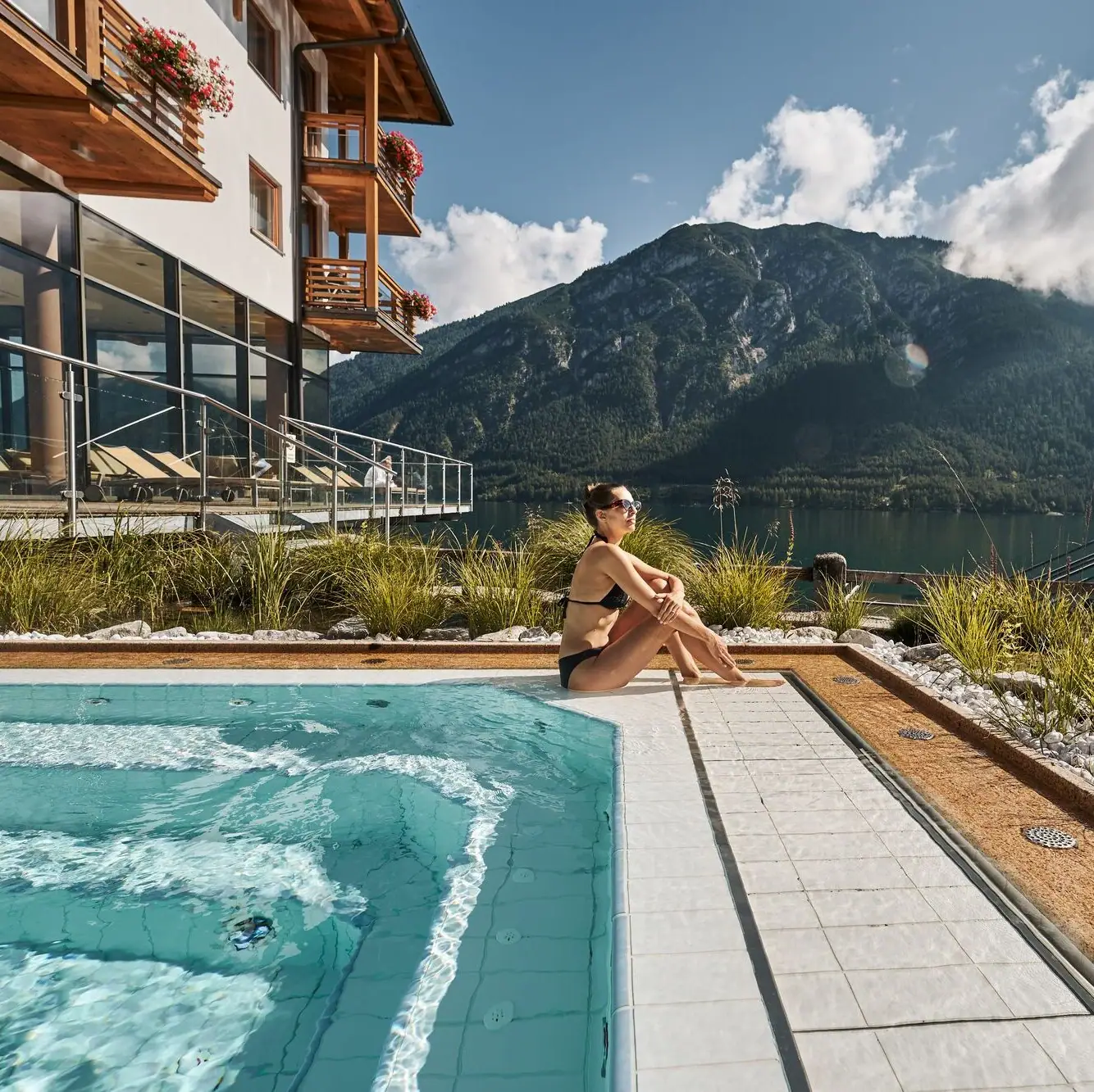 Whirlpool Eine Frau sitzt an einem Pool mit einem Berg im Hintergrund.