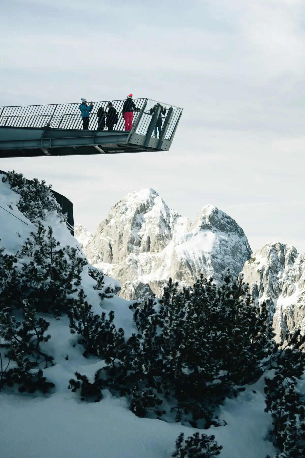 Geführte Wandertouren Menschen stehen auf einer Brücke über einem schneebedeckten Berg.
