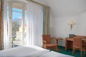 Zimmer mit Bett, Schreibtisch und Stuhl.