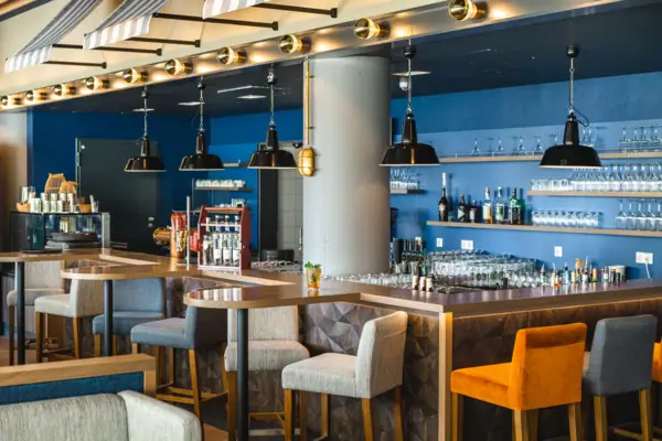 Restaurant und Bar im aja Warnemünde Eine Bar mit Stühlen und Gläsern.