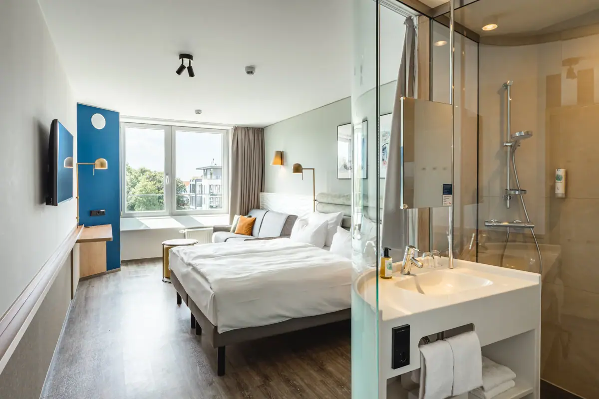 Neues Doppelzimmer im aja Warnemünde Ein Zimmer mit einem Bett und einer Dusche.
