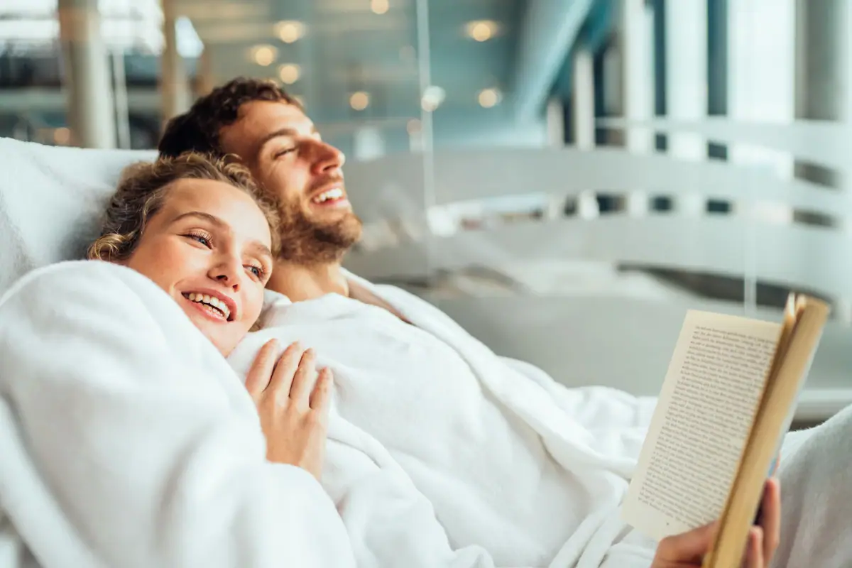 Ein Mann und eine Frau liegen lächelnd in einem Bett.