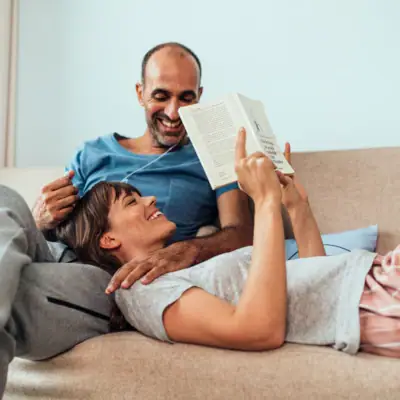 Ein Mann und eine Frau liegen auf einem Sofa und lesen ein Buch.