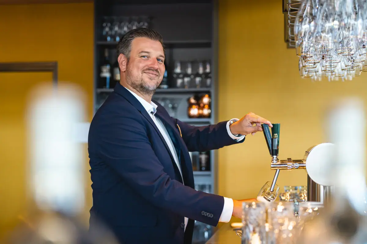 Barkeeper Ein Mann im Anzug zapft Bier an einem Hahn.