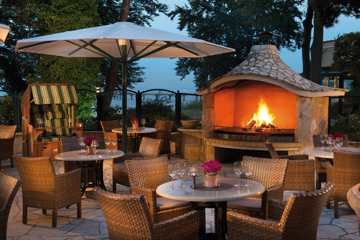 Ein Tisch und Stühle um eine Feuerstelle im Freien.