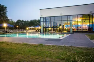 Außenpool beleuchtet Ein Gebäude mit einem Schwimmbecken und Rasen.