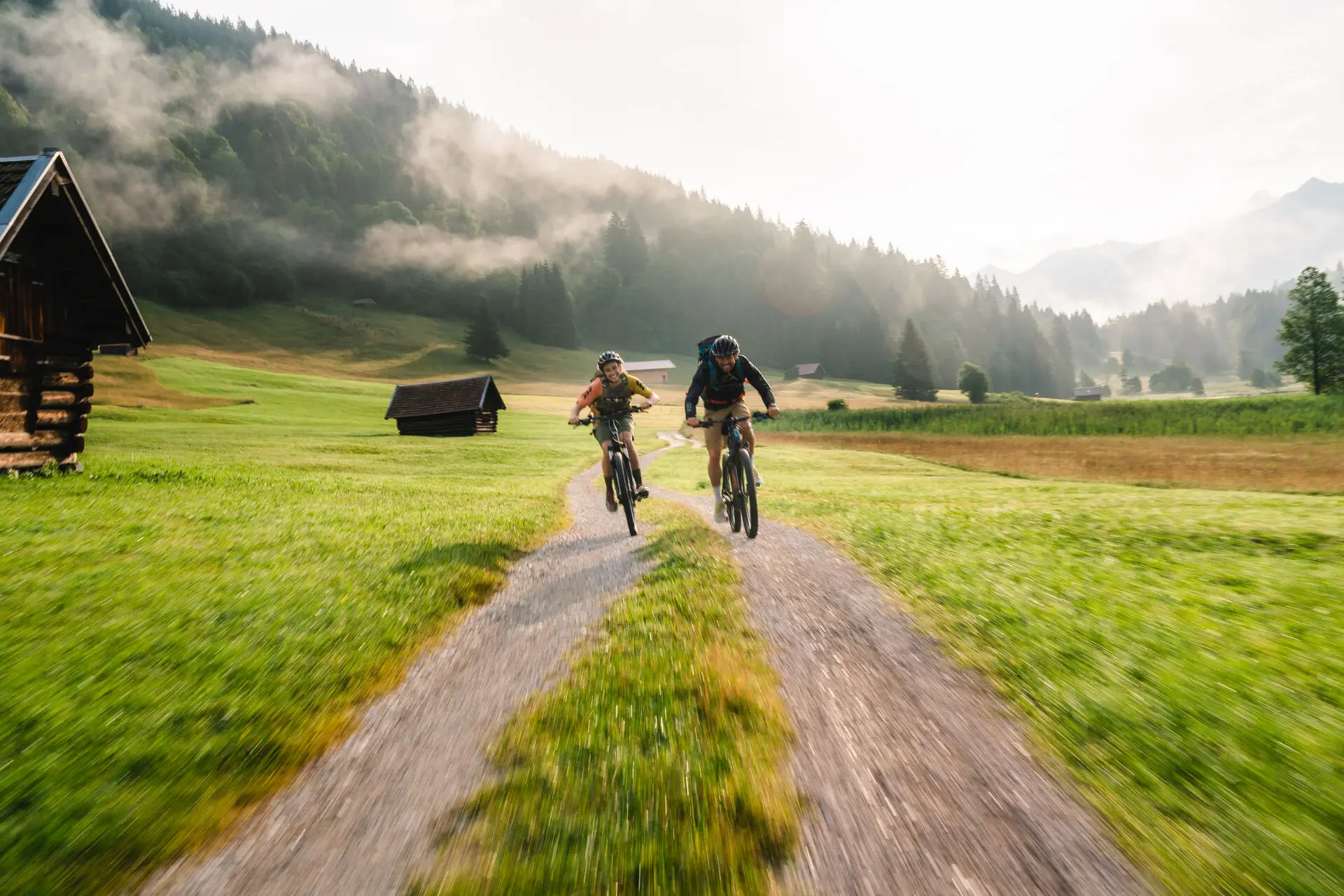 Zwei Personen fahren auf einem Feldweg Fahrrad