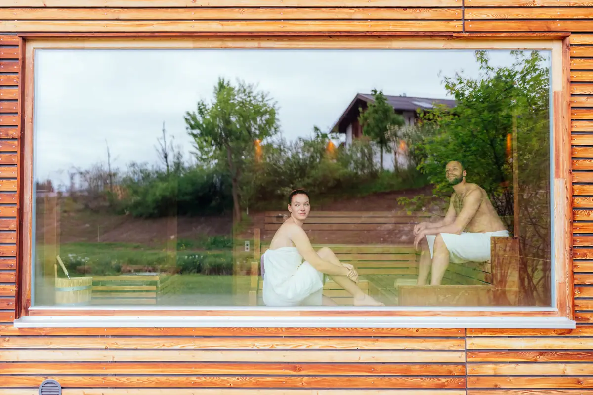 Ein Mann und eine Frau sitzen auf einer Bank in einer Sauna.