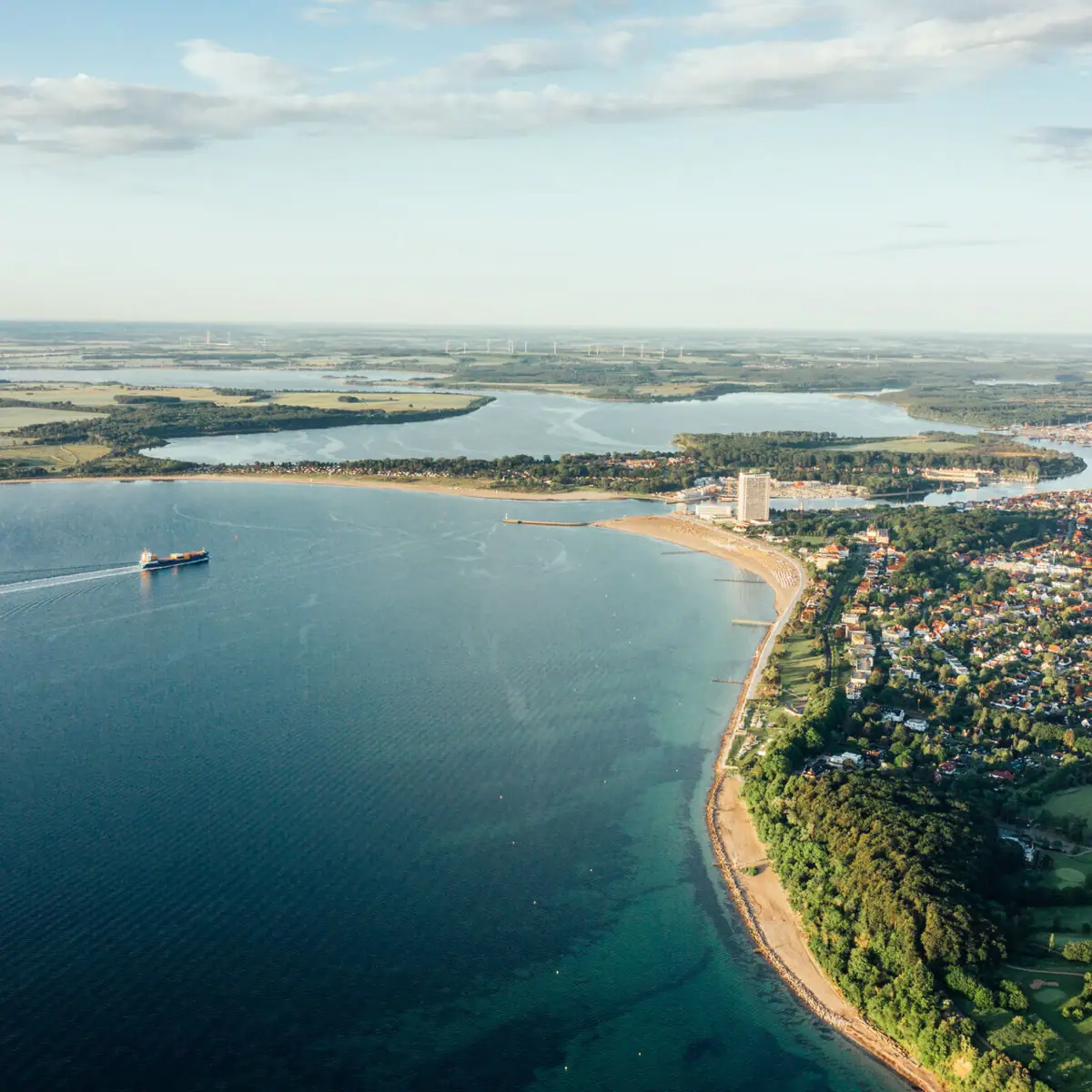 Lübecker Bucht Luftaufnahme der Ostseeregion von Travemünde und einer Küstenstadt unter bewölktem Himmel.