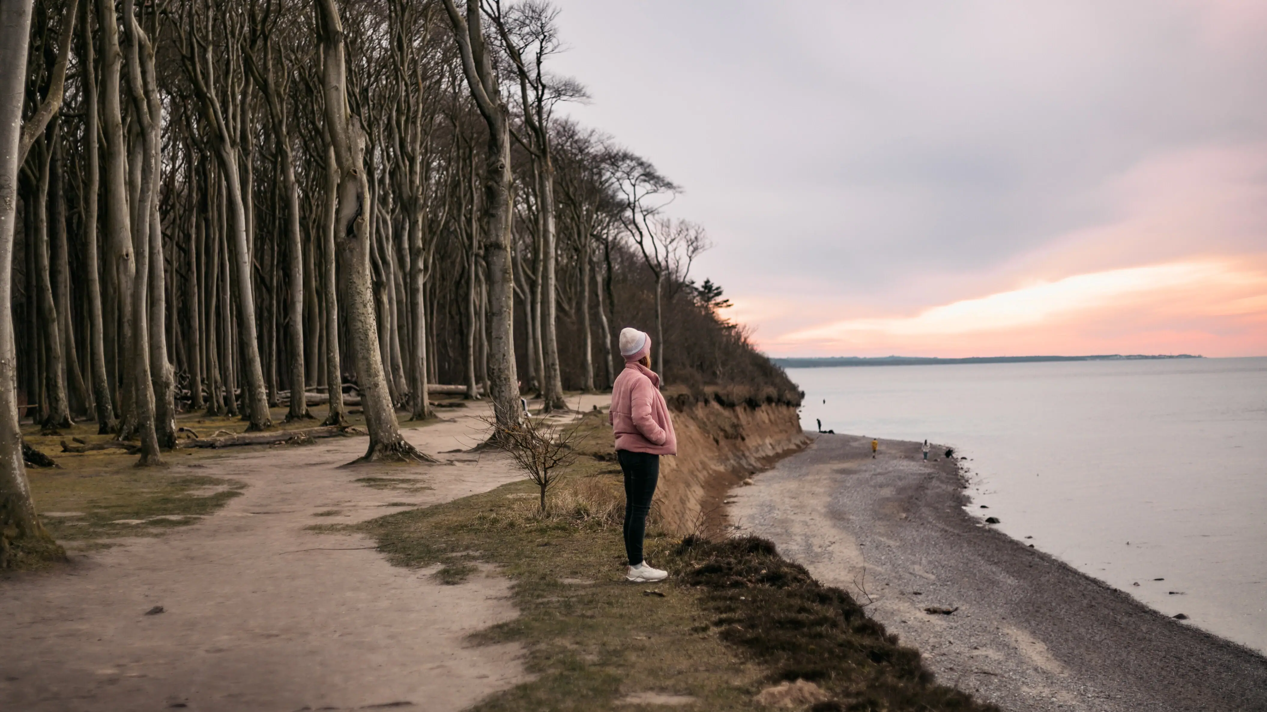 Gespensterwald Eine Frau steht auf einem Weg am Wasser.