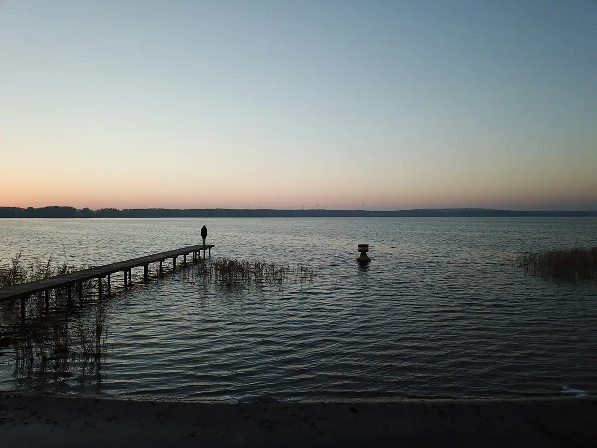 Eine Person steht auf einem Steg im Wasser.