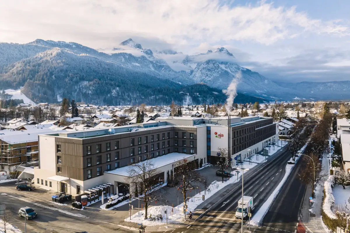 aja Garmisch-Partenkirchen Ein Gebäude mit Schnee am Straßenrand im Freien.