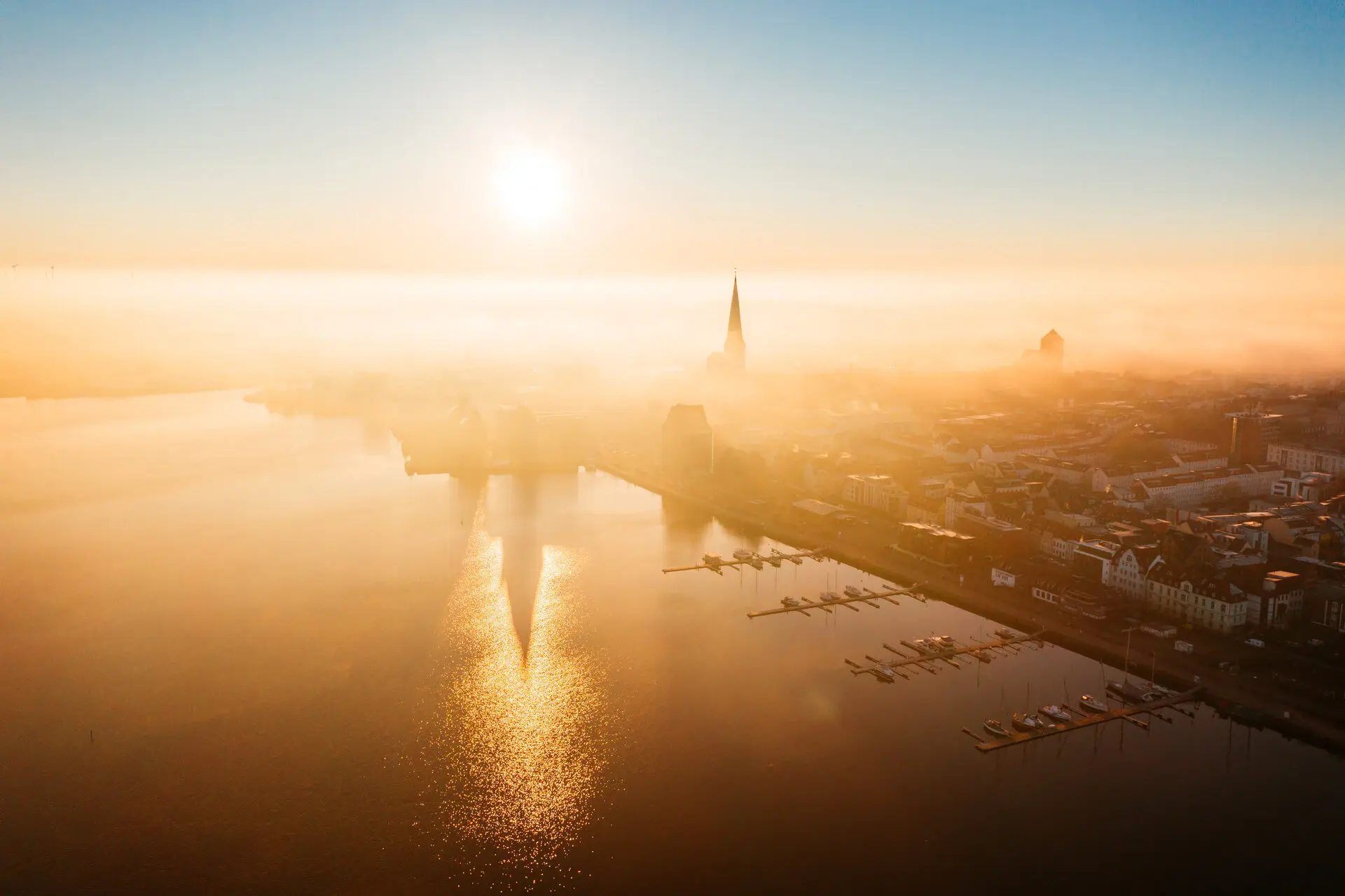 Eine Luftansicht von Rostock und dem angrenzenden Wasser bei aufgehender Sonne.