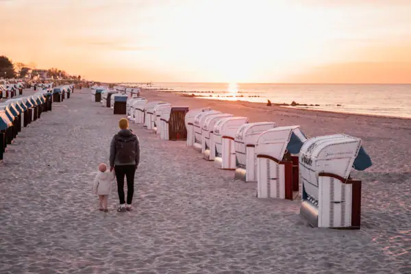 Strand von Grömitz Eine Frau und ein Kind gehen am Strand entlang.