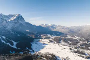 Garmisch-Partenkirchen Verschneite Berglandschaft mit einer Stadt und Bäumen.
